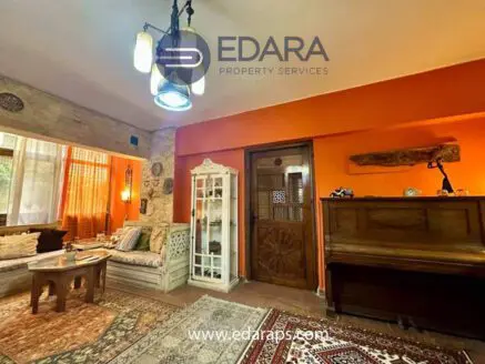 Cozy living room featuring orange walls, wooden furniture, and decorative elements.