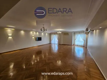 Large living room featuring wooden flooring and natural light from windows.