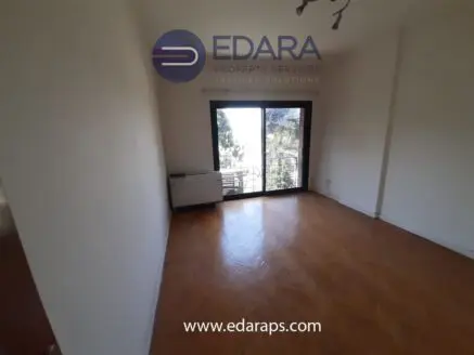 Interior view of an empty room with parquet flooring and a balcony door leading outside.