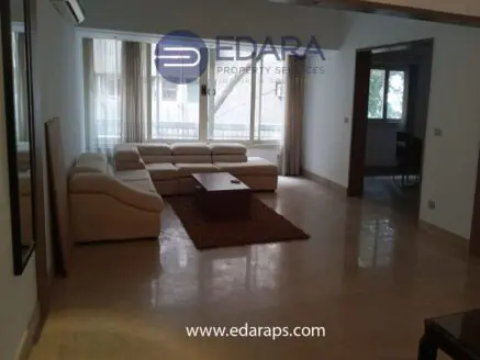 Spacious living room featuring a white sectional sofa and a wooden coffee table on a light-colored floor.