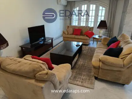 Living room featuring two beige sofas with red cushions and a coffee table in front of a television.