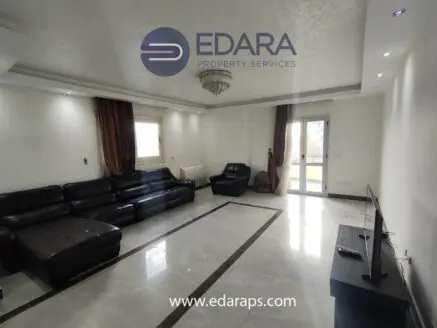 Spacious living room featuring a black leather sofa set and a television on a stand.