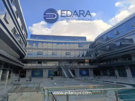 Interior view of a modern commercial building with glass walls and escalators.