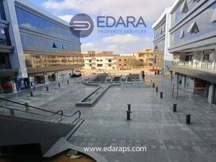View of a modern commercial plaza in Cairo with glass buildings and a fountain area.