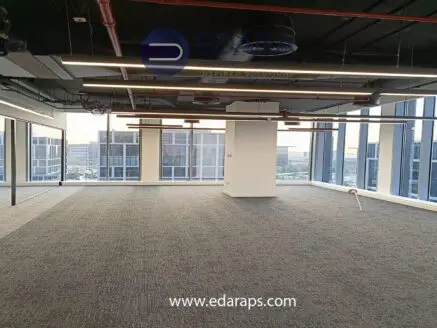 Empty office space featuring large windows and modern lighting fixtures in a commercial building.