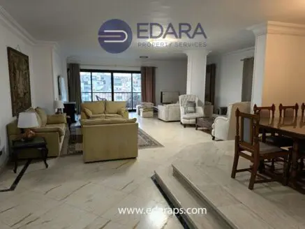 Spacious living room featuring a sofa set, dining table, and decorative elements in a neutral color scheme.