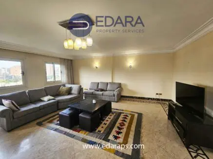 Spacious living room featuring a gray sofa set, coffee table, and television against a light-colored wall.