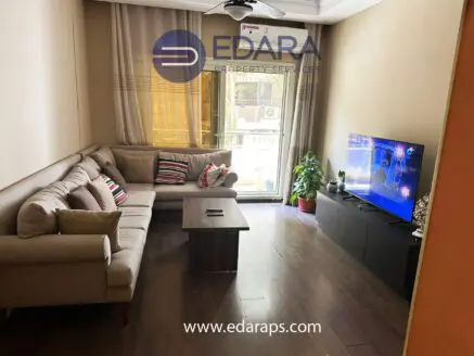 Modern living room featuring a beige sofa, coffee table, and a television on a black unit.