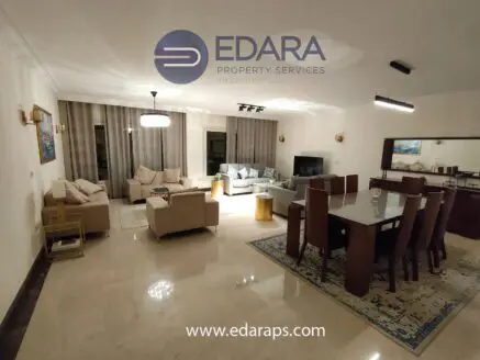 Spacious living room with beige sofas, dining table, and decorative elements in a well-lit interior space.