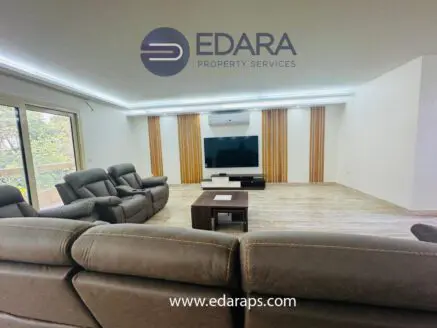 Spacious living room featuring reclining sofas, a coffee table, and a wall-mounted television.