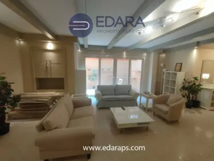 Modern living room featuring two sofas, a coffee table, and decorative plants in a neutral color scheme.