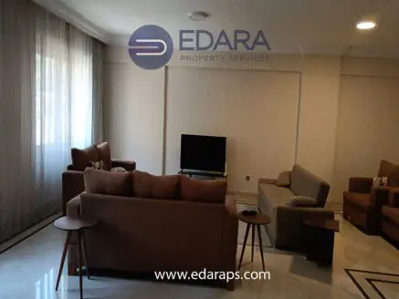 Living room featuring two sofas, a coffee table, and a television set against a light-colored wall.