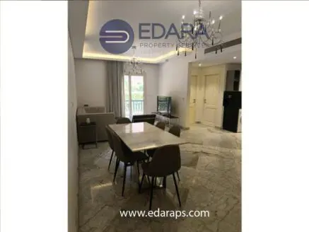 Dining area featuring a marble table surrounded by gray chairs in a well-lit room.