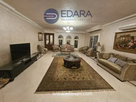 Spacious living room featuring a sofa set, coffee table, and decorative elements in a neutral color scheme.