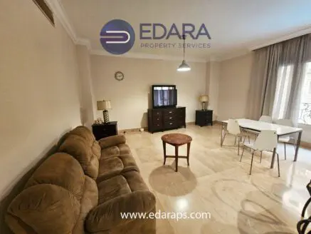 Cozy living room featuring a brown sofa, dining table, and decorative lamps in a neutral color scheme.