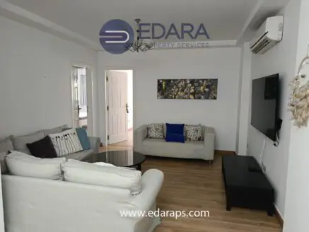 Modern living room featuring a light-colored sofa, a coffee table, and a wall-mounted television.