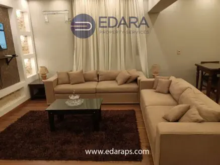 Spacious living room featuring a beige sectional sofa, glass coffee table, and decorative rug.