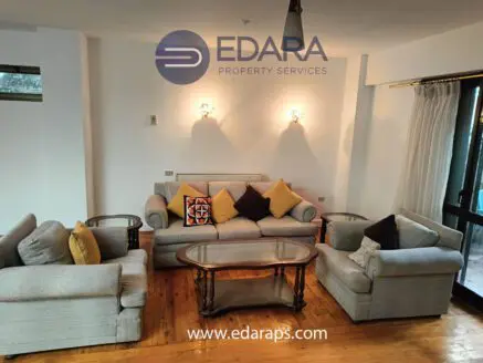 A living room setup featuring a gray sofa set with decorative cushions and a glass coffee table.