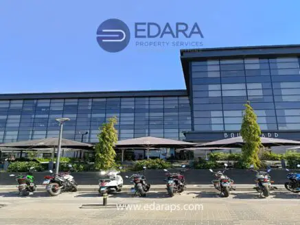 A modern commercial building with large glass windows and parked motorcycles in front.