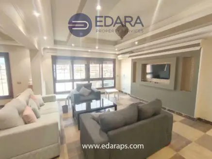 Spacious living room featuring light-colored sofas, a coffee table, and a wall-mounted television.