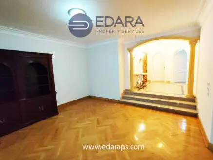 Interior view of a room featuring wooden flooring and an archway leading to another space.