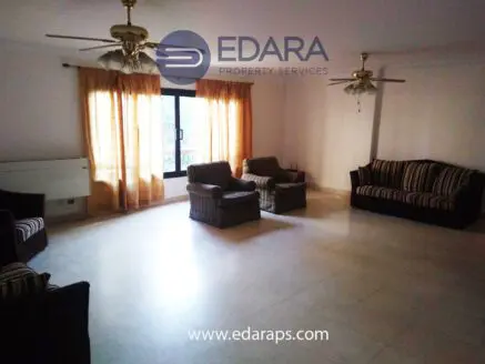 Spacious living room featuring striped sofas and armchairs with large windows and natural light.