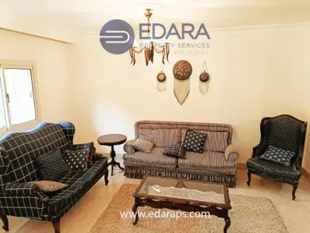 A living room featuring a blue and white patterned sofa set, a small round table, and decorative wall elements.