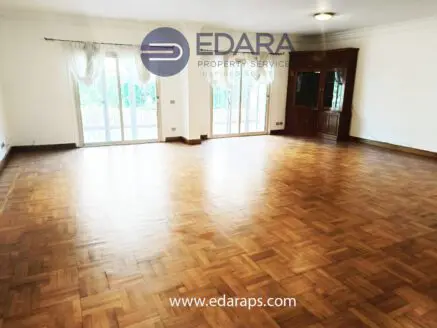 Bright and spacious living room featuring wooden parquet flooring and large windows.