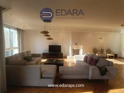 Spacious living room featuring a light-colored sofa, television, and decorative lighting fixtures.
