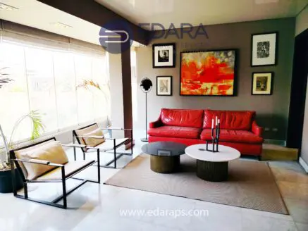 Contemporary living room featuring a red sofa, glass coffee table, and framed artwork on the walls.