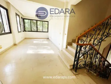 Bright interior of a residential space with large windows and a staircase.
