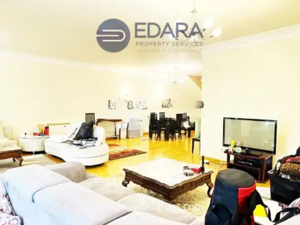 Interior view of a spacious living room featuring a sofa, dining table, and television.
