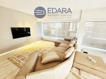 Contemporary living room featuring a sectional sofa and a wall-mounted television with natural light.