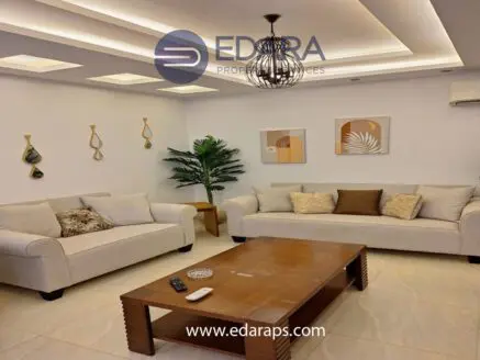 Living room featuring two beige sofas, a wooden coffee table, and decorative wall art.