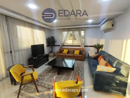 Contemporary living room featuring a sofa, chairs, and a television with natural light from large windows.