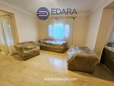 Living room featuring two wrapped sofas and a window with sheer curtains.
