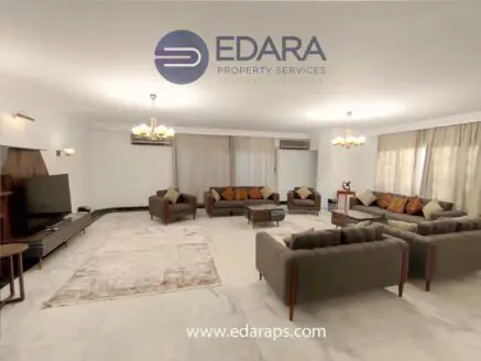Spacious living room featuring a sofa set, coffee table, and television against a neutral backdrop.