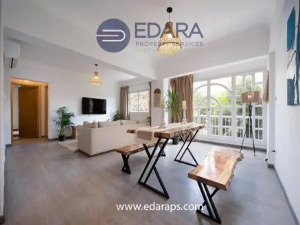 Contemporary living room featuring a wooden dining table and large windows with natural light.