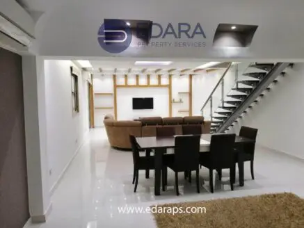 Interior view of a modern living room with a dining table and staircase in a residential space.