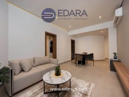Contemporary living room featuring a light-colored sofa, round coffee table, and dining area with chairs.