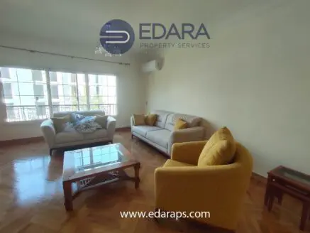 A living room featuring a light-colored sofa, a yellow armchair, and a wooden coffee table.