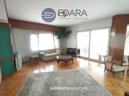 Living room featuring a beige sofa, round coffee table, and large windows with natural light.