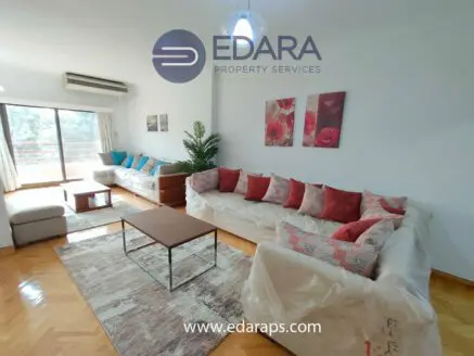 Spacious living room featuring a sectional sofa, coffee table, and decorative cushions with floral artwork on the wall.