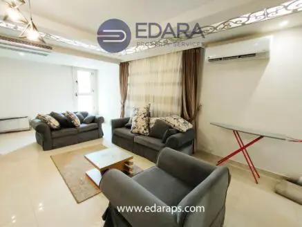 Living room featuring gray sofas with decorative pillows and a glass coffee table on a tiled floor.