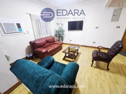 Living room featuring a brown leather sofa, a green armchair, and a wooden coffee table.