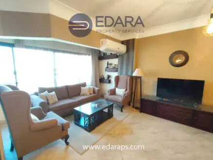 Modern living room featuring a beige sofa set, coffee table, and television on a wooden cabinet.
