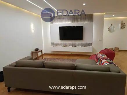 Modern living room featuring a gray sofa and a wall-mounted television unit with decorative elements.