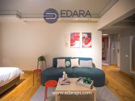 Contemporary living room featuring a green sofa, decorative table, and wall art in a neutral color scheme.