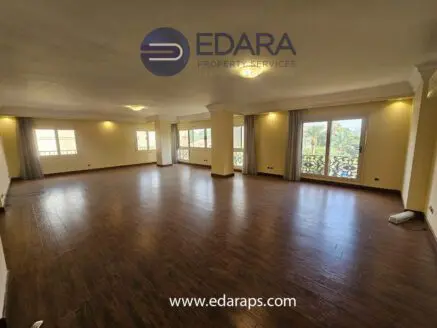 Large, unfurnished living room with wooden flooring and multiple windows allowing natural light.
