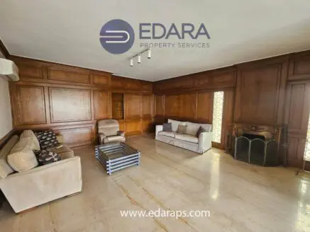 Living room featuring wooden paneling, a beige sofa set, and a glass coffee table.